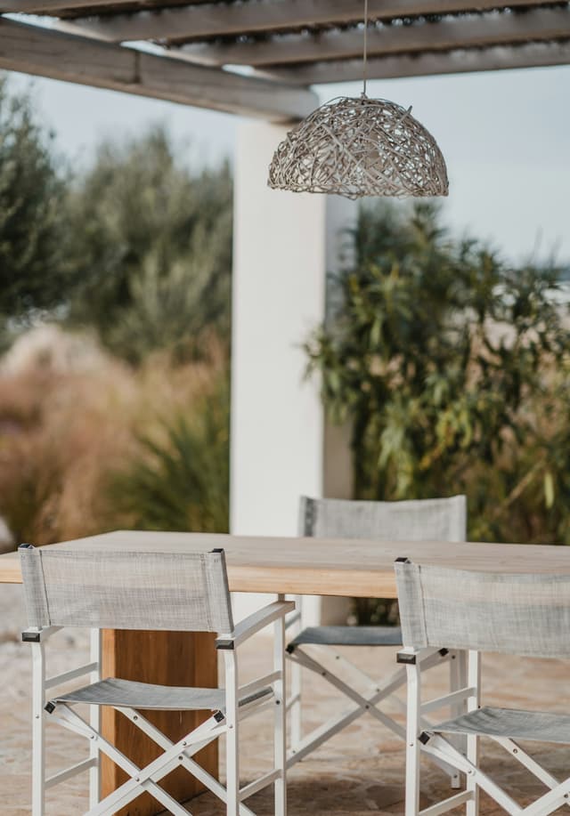 Mediterranean patio with a rattan pendant, wooden table, and director chairs
